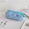 Detail of light blue quilted pencil case featuring a large tooth zipper and soft texture - Blue