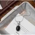 Detailed close-up of a silver snake chain necklace with an oval black resin stone pendant - Silver with Black Oval Pendant