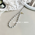 Detail of beaded phone strap featuring pearls and a golden rose charm on starry fabric - Pearl Rose Alloy