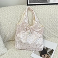 Nahaufnahme der rosa Samt-Tragetasche mit Bärenprint und Markenlabel auf Sofa - Rosa