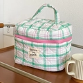 Detailed view of quilted cotton cosmetic bag featuring green plaid pattern and logo label - Verdant