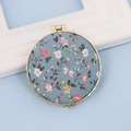 Blue floral fabric folding compact mirror with golden round frame on light blue background - Round / Round Blue