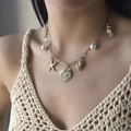 Gold charm necklace with starfish shell seahorse and pearl pendants on a model - Multi-Pendant Shell Starfish Conch
