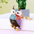 Sparkling metal owl keychain with colorful crystals and golden ring on white surface - A430 Owl Q Blue