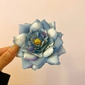 Detalle de pinza de rosa de tela en degradado azul sostenida a mano con estambres amarillos - Clip de pico de pato con flor de rosa azul