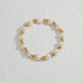 Close-up of golden beads and white pearls bracelet with star charm on textured surface - Star Pearl Beaded String