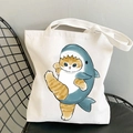 White canvas tote bag featuring a cute shark cat cartoon print on a black iron chair - Cat with Shark Hat