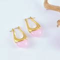 Détail de boucles d'oreilles dorées en U avec résine rose sur une surface blanche nette - Rose