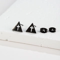 Detailed macro view of black triangular stud earrings with hollow cross and metal backs - Triangle Cross Style (175) / Black