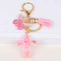 Dettaglio di portachiavi a croce in resina rosa con glitter, farfalla e nappa decorativa - Rosa (Y006-1)