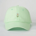Détail de la broderie marguerite blanche et des coutures sur la casquette vert menthe - Taille unique / Vert clair