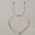 Detalle de pulsera de cuentas tejidas rosa con cordón ajustable y extremos de metal dorado - Cuarzo Rosa Trenzado