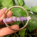 Golden round hair clip with natural purple crystal stones held against green plants - Gold Circle Lavender Amethyst Chips