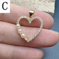 Vista dettagliata di un ciondolo a cuore dorato con perle bianche e zirconi in mano - Stile C-Ciondolo a Cuore con Perle e Zirconia