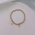 Close-up of gold beaded stretch bracelet with baroque pearl and crescent moon charms - Gold-Moon