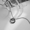 Macro shot of silver and black interlocking triple ring pendant on silver box chain - Black