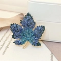 Ahornblatt-Brosche mit blauen Kristallen und Gold-Finish auf eleganter Schmuckschatulle - Azurblaues Ahornblatt