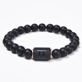 Detailed macro of black onyx beaded bracelet with Gemini symbol and rose gold spacers - Gemini