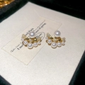 Dettaglio di eleganti orecchini in perle dorate e zirconi su scheda beige - Oro/Bianco