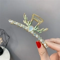 Dettaglio molletta per capelli a corno dorata con strass blu e perle nella mano - Corno di Cervo Oro con Perle e Strass