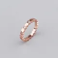 Detail view of rose gold scalloped ring band with micro-set zircon stones on gray background - Ring / Rose Gold
