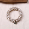 Close-up of woven pearl hair scrunchie with a round gold Morave brand metal charm - Large Pearl Style