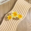 Drei-Gänseblümchen-Haarklammer mit gelb-weißem Farbverlauf auf einem Holztablett - Dreifache siebenstrahlige Blüten / Gelb