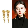 Matte gold floral tassel earrings on model featuring elegant long petal design - Golden 3D Floral Tassel / 4# Gold Color With Silver Earring Post