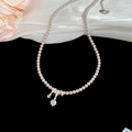 Detailed view of pink pearl necklace with a sparkling zircon pendant on black surface - Pink