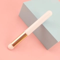 Detail of round head lip brush with gold ferrule and white bristles on pink background - White