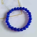 Single strand 8mm blue cat eye bead bracelet on a marble surface with a decorative card - Royal Blue Cat's Eye