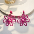 Detail of fuchsia hand-woven raffia flower earrings on a white ceramic plate - Rose Red
