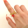Golden bow ring with red round bead pendant in a minimalist stainless steel design - 18K Gold Plated Red Bow Ring (9816)