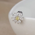 Macro shot of silver flower helix stud with yellow zircon on white ceramic edge - Yellow Center Stone Flower