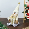 Detail of plush snowman doll in beige knit hat with gift box on white plastic sled base - Gold Skiing Figurine Snowman