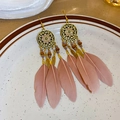 Détail macro de boucles d'oreilles bohèmes avec plumes violettes et disques dorés vintage - Crochet Plume Émail Rose