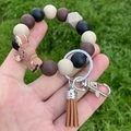 Silicone bead keychain bracelet with brown elk charm and leather tassel on grass - Black Brown