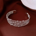 Detalle de brazalete plateado de varias capas con cuentas grabadas sobre seda - Plateado