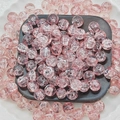 Macro shot of pink cracked glass beads with icy textures in a decorative display tray - Pink