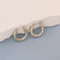 Detail view of silver oval hoop earrings with woven texture on white stone background - Silver Woven Scale Hoop