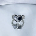 Detail of silver heart ring with clear and black teardrop stones on a reflective surface - Style 2 (Heart Black Gem)