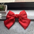 Detailed view of the red satin fabric texture on a large elegant bow hair clip - Red