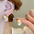 Gros plan de boucles d'oreilles ovales dorées et blanc perle portées par un mannequin - 18# Tige en Argent - Boucles d'Oreilles Géométriques Bicolores Dorées Mates