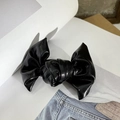Detalle de una pinza para el pelo con lazo de cuero sintético negro brillante sobre tela vaquera - Negro