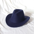 Detail of navy blue felt fedora hat with wide brim on white textured fabric backdrop - Navy Blue
