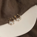 Close-up of baroque pearl earrings with five white pearls in gold setting on a tray - Style 3