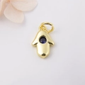 Macro shot of gold Hamsa Hand charm with a deep blue zircon stone on white background - Dark Blue Zirconia