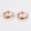 Detalle de pendientes huggie de oro rosa con diseño cruzado y piedras de circonio - Oro rosa