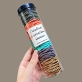 Nahaufnahme einer Hand mit Zylinder voller bunter, hochelastischer Haargummis - 7# Morandi-Farben 100 Stk. Gedreht Dose