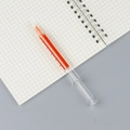 Orange syringe-shaped highlighter with scale markings on a spiral grid notebook - Orange Red